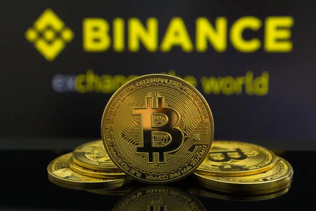 A big Bitcoin cryptocurrency coin in the centre and other bitcoin coins from both side in front of Binance crypto market . The pyramid of bitcoin coins on a blue Binance cryptostock exchange background. Los Angeles, US - 18.07.2019.