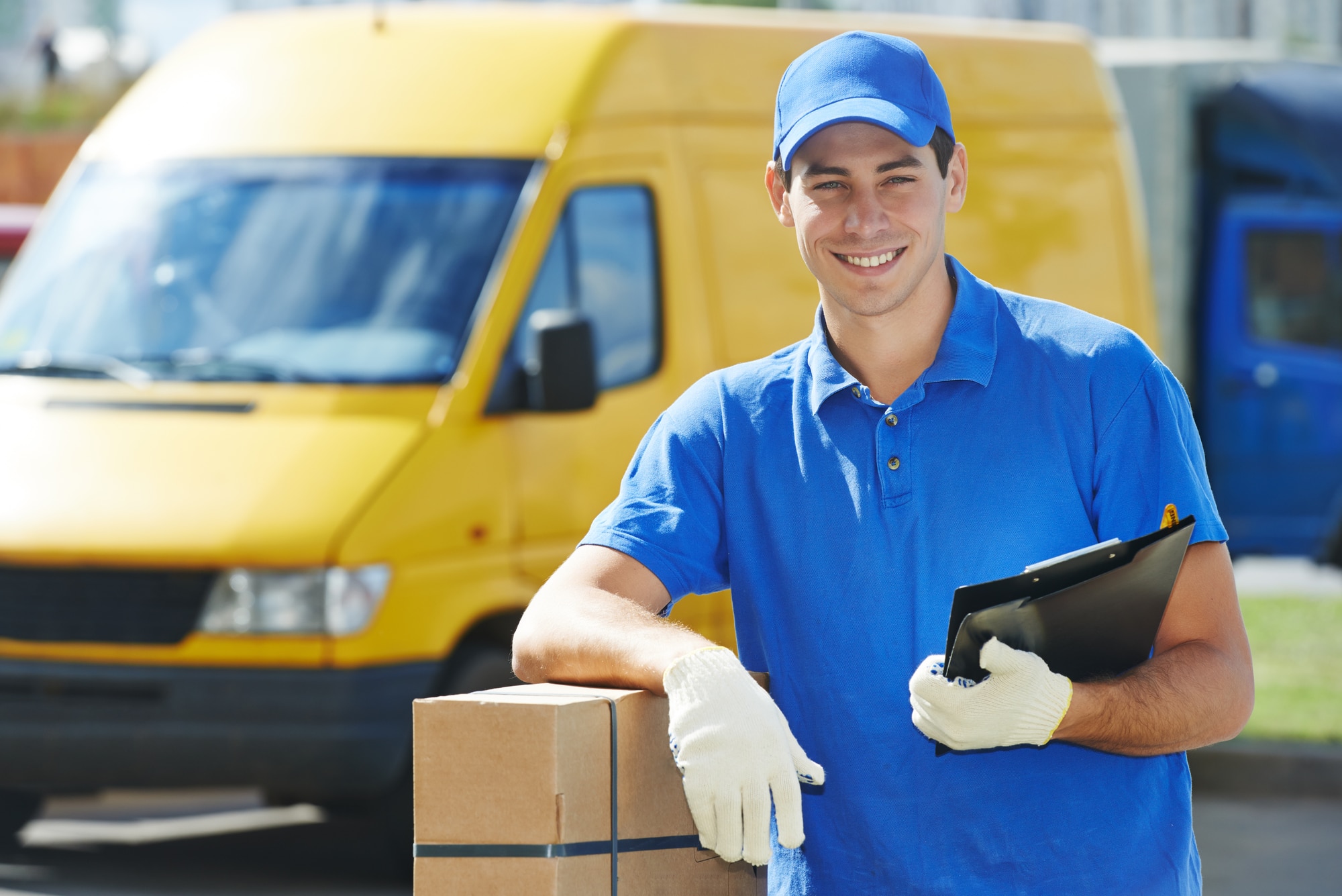 Smiling young male postal delivery courier man in front of cargo van delivering package