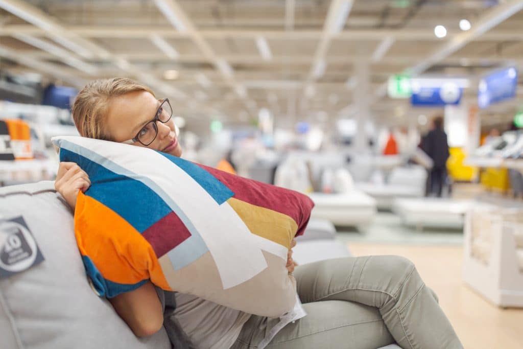 Pretty, young woman choosing the right furniture for her apartment in a modern home furnishings store (color toned image; shallow DOF)