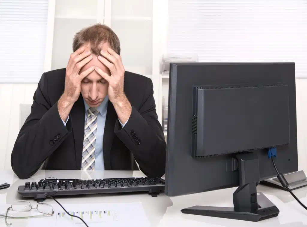 Overworked businessman frustrated and stressed in his office with computer - headache.