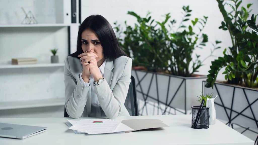 Upset woman in office at work desk
