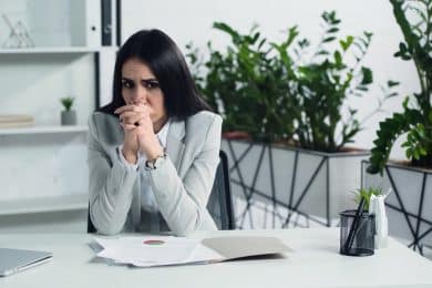 Upset woman in office at work desk