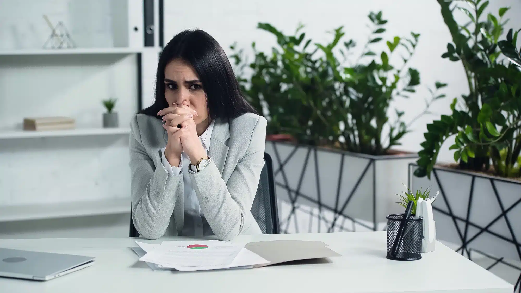 Upset woman in office at work desk