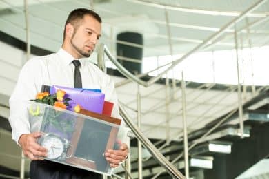 Fired businessman packed his bags and leaving office. He is looking sad.