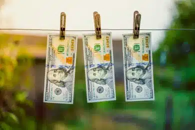 Three hundred dollar bills hanging on a clothes dryer pinned with clothespins close-up on a blurred background. Money laundering on a small scale. Corruption scheme for illegal receipt of money