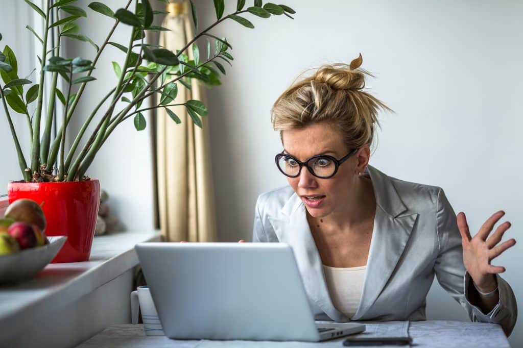 Nervous business woman screaming loudly at her laptop in office. Stress.