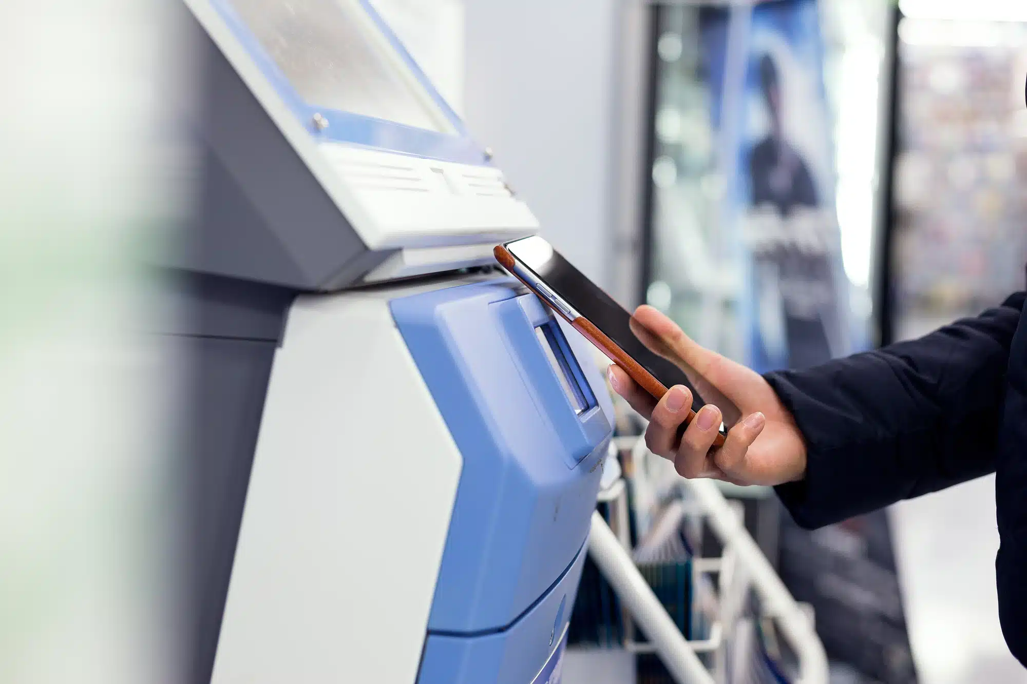 Woman connecting cellphone and ticketing machine