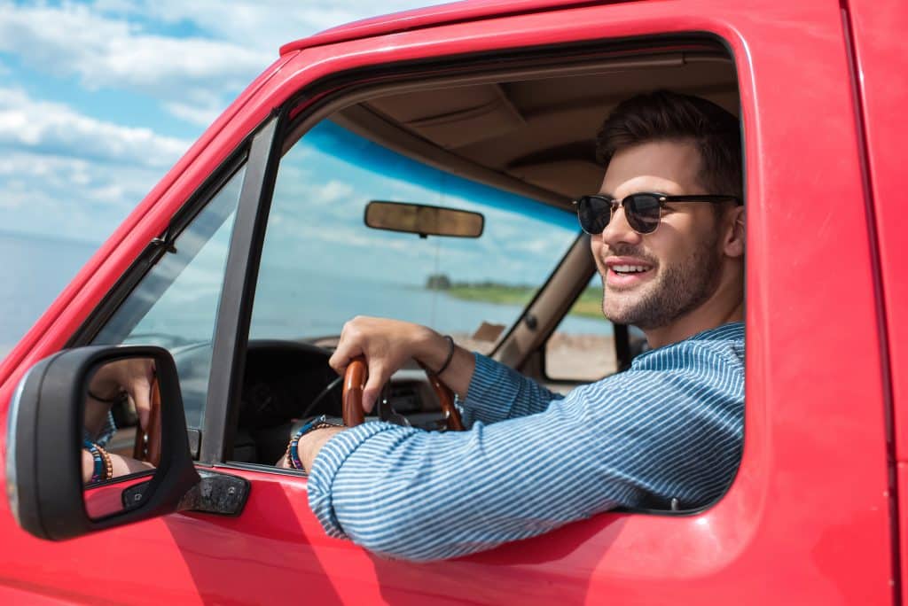 A man is driving a red car