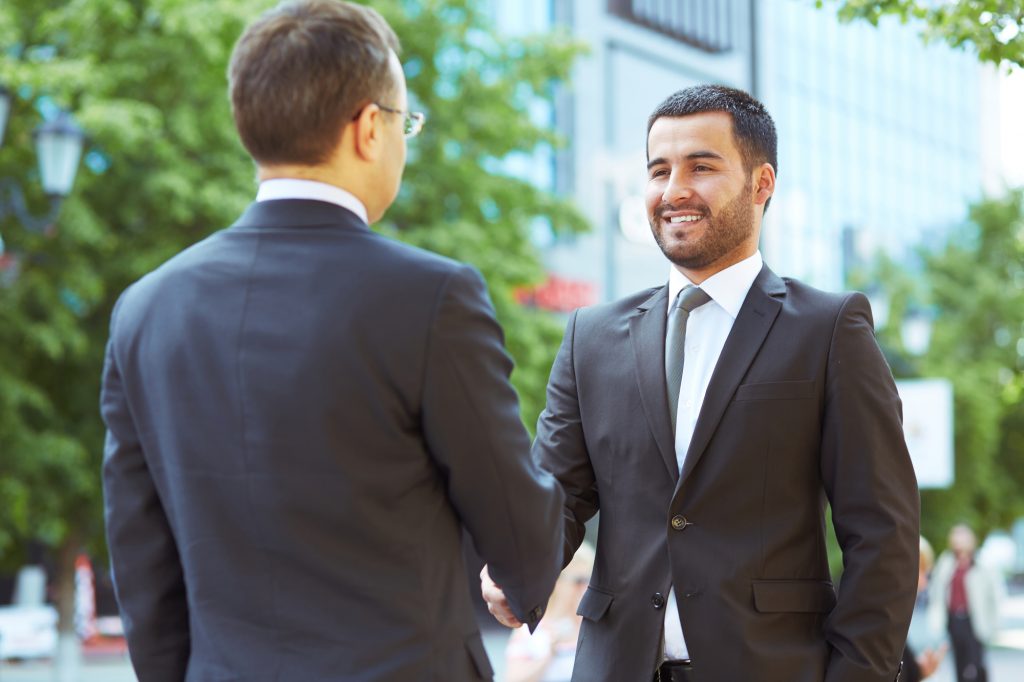 Satisfied partners shaking hands in the urban surroundings