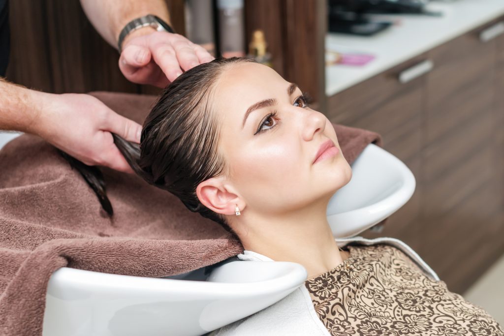 After washing hair of woman head on towel in sink in hair salon.