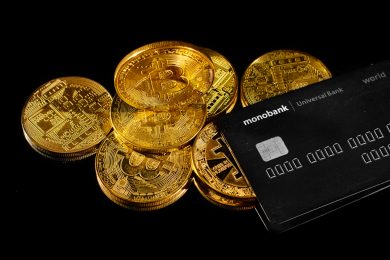 Lutsk, Ukraine - May 1, 2021: Golden coin with bitcoin logo and credit card by monobank. Crypto currency BTC and bitcoin rewards card by Universal bank. E-cash payment or digital electronic money