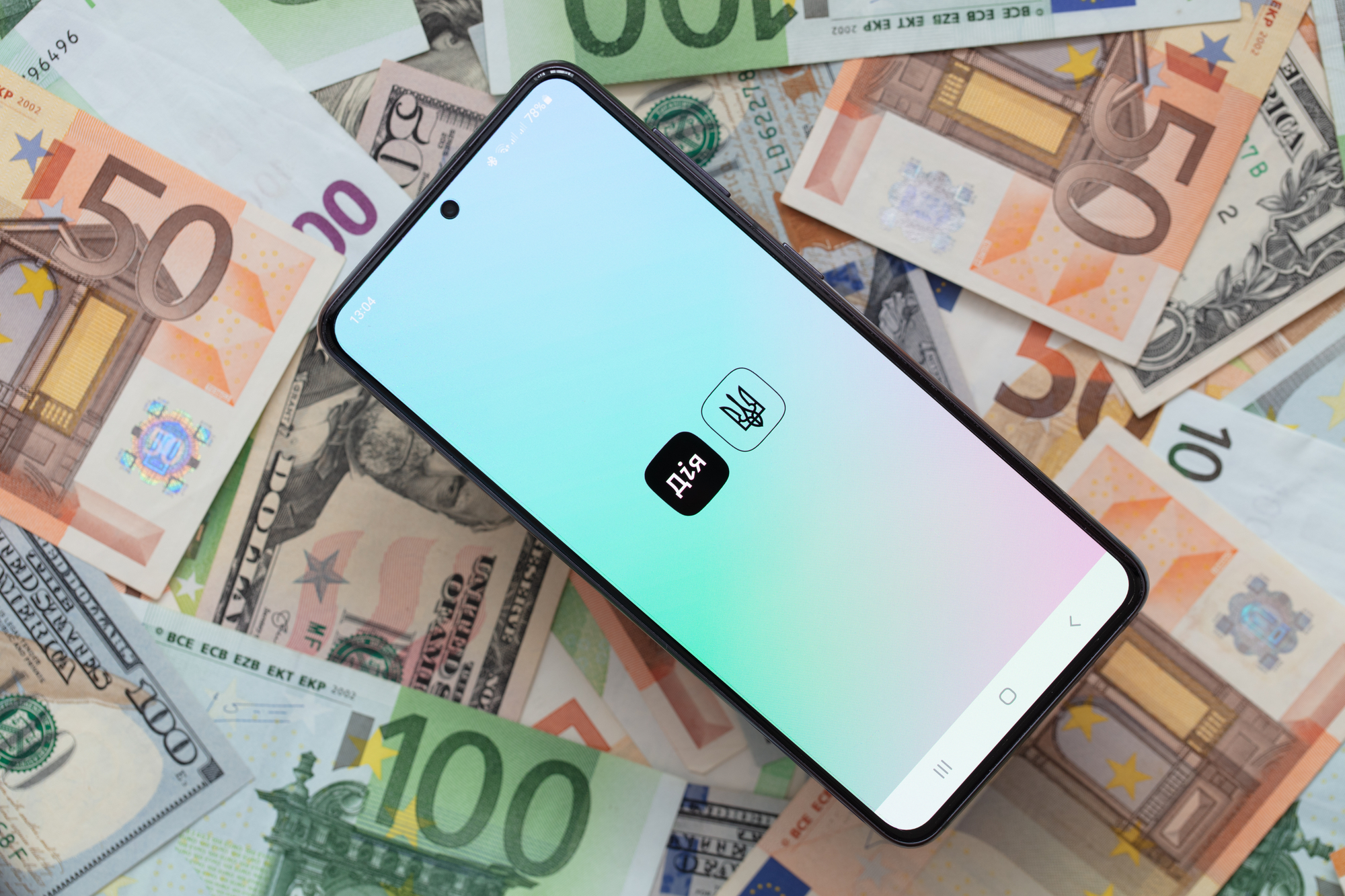Kyiv, Ukraine - December 1, 2021: smartphone screen with Diya mobile  application on US dollar and euro banknotes background. Ukraine in a smartphone.