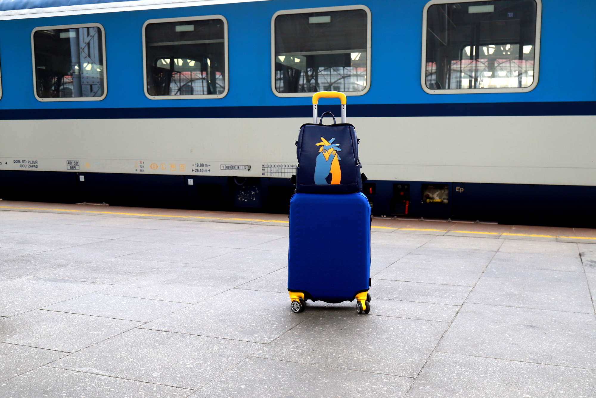 Suitcase and bag in colors of Ukraine flag at railway station, Prague, Czech Republic. Journey of Ukrainians, refugees, migrants. Travel, vacation, weekends, refugee, emigrant