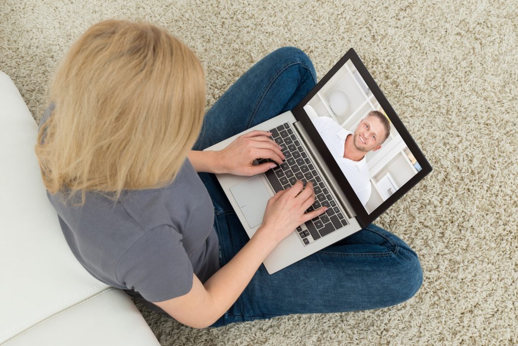 Young Woman Online Video Chatting With Man On Laptop In Living Room