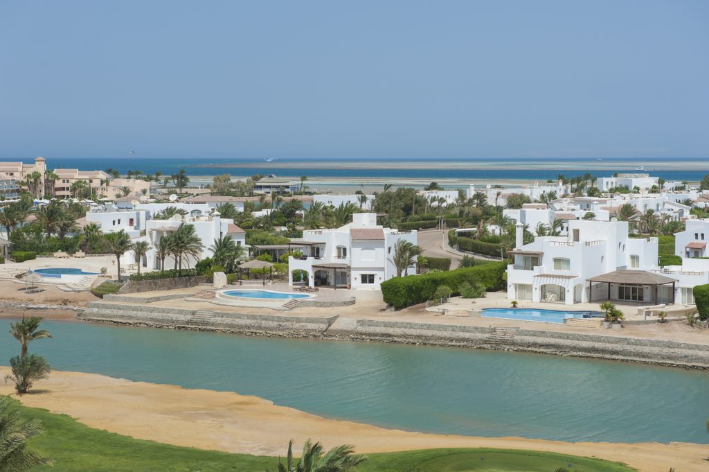 Aerial view over large lagoon with luxury waterfront villa residences with swimming pool in tropical coastal resort town