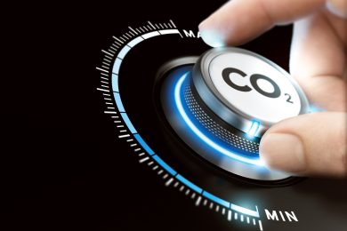 Man turning a carbon dioxyde knob to reduce emissions. CO2 reduction or removal concept. Composite image between a hand photography and a 3D background.