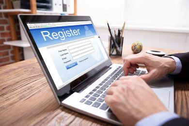 Businessman's Hand Filing Online Registration Form On Laptop