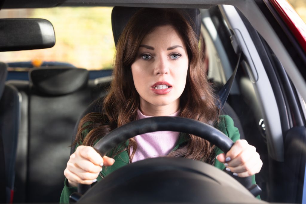 Portrait Of A Shocked Young Woman Driving Car