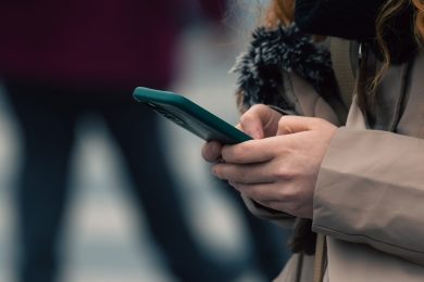 Дівчина тримає телефон на вулиці