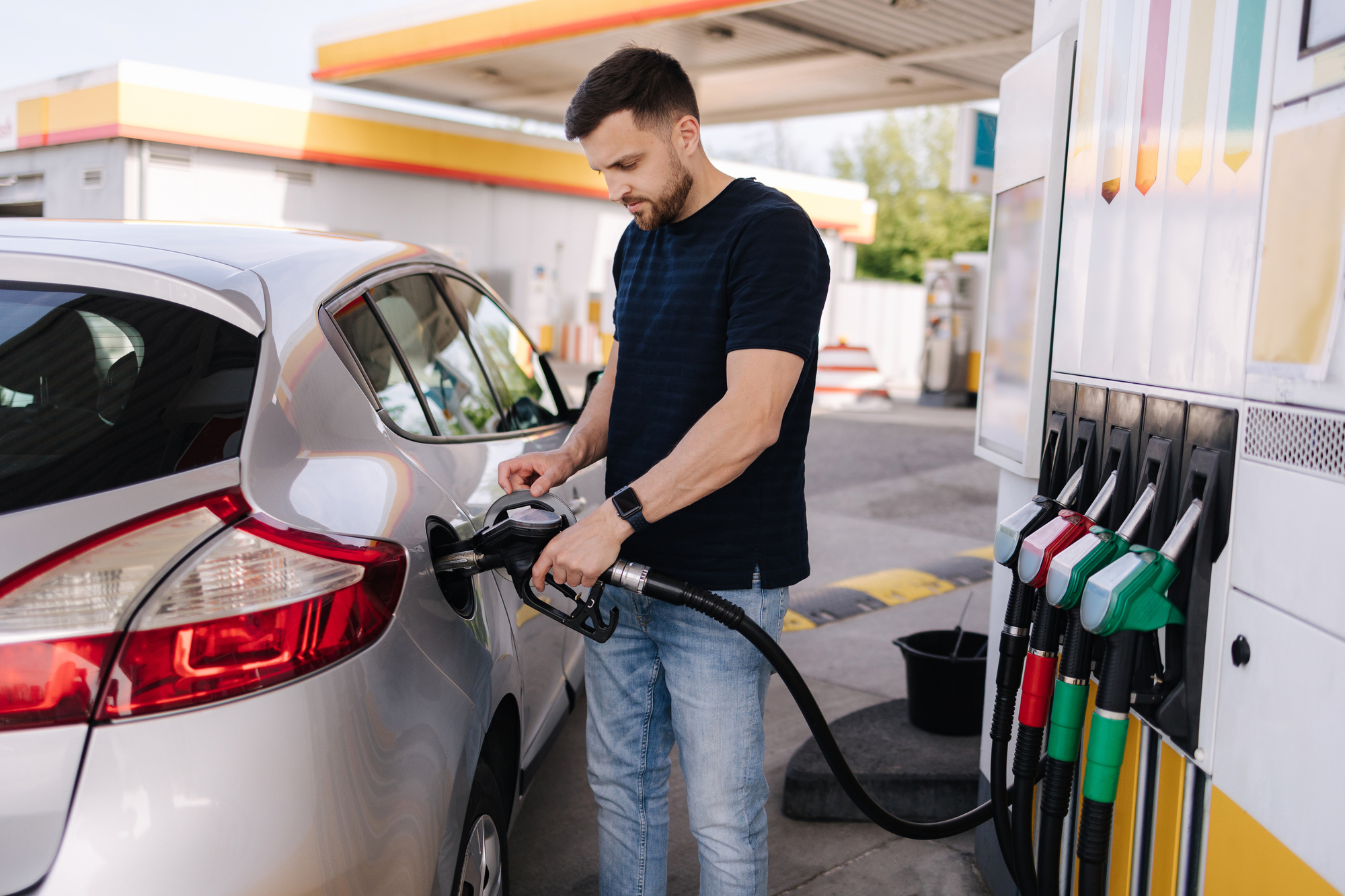 Handsome young man refuelling car at gas station. Female filling diesel at gasoline fuel in car using a fuel nozzle. Petrol concept. Side view. High quality photo