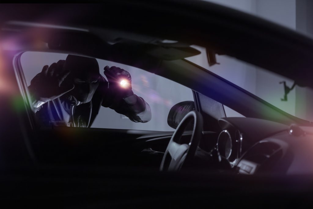 Car Robber with Flashlight Looking Inside the Car. Car Security Theme.