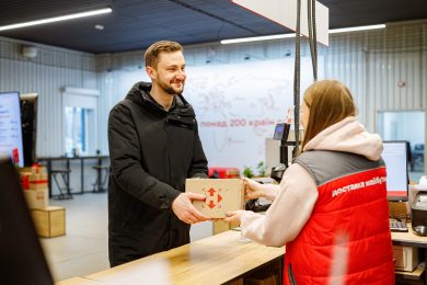 чоловік у чорній куртці забирає посилку в новій пошті