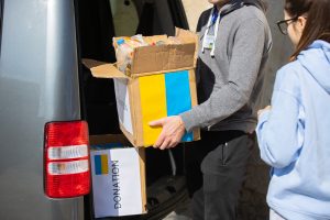 волонтер держит коробу возле авто