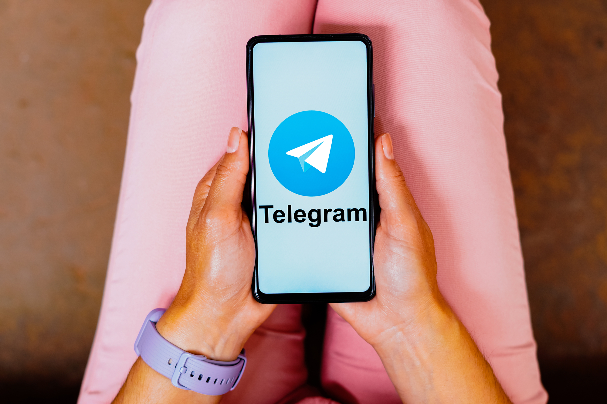 девушка держит в руках телефон, на котором открыт Telegram