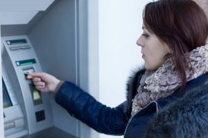 Жінка користується банкоматом для зняття готівки