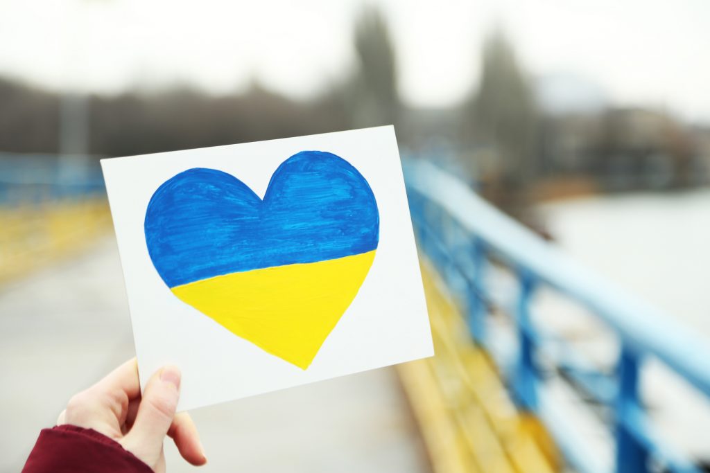 дівчина тримає малюнок серця в кольорах прапора України
