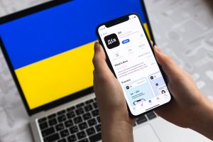 дія застосунок на телефоні який тримає жінка, на фоні ноутбук з українським прапором