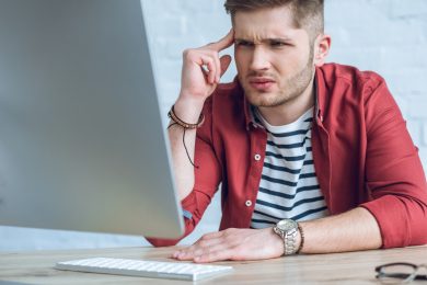 хлопець у червоній сорочці і футболці в лінійку за екраном ноутбука