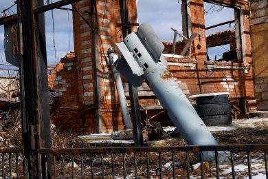 ракета застрягла в землі біля розваленого будинку з червоної цегли