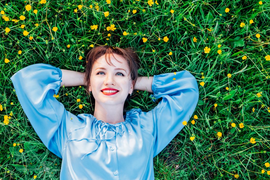 жінка в блакитній сорочці лежить на траві