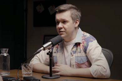 ярослав ажнюк. чоловік у світлій сорочці біля мікрофона на чорному фоні