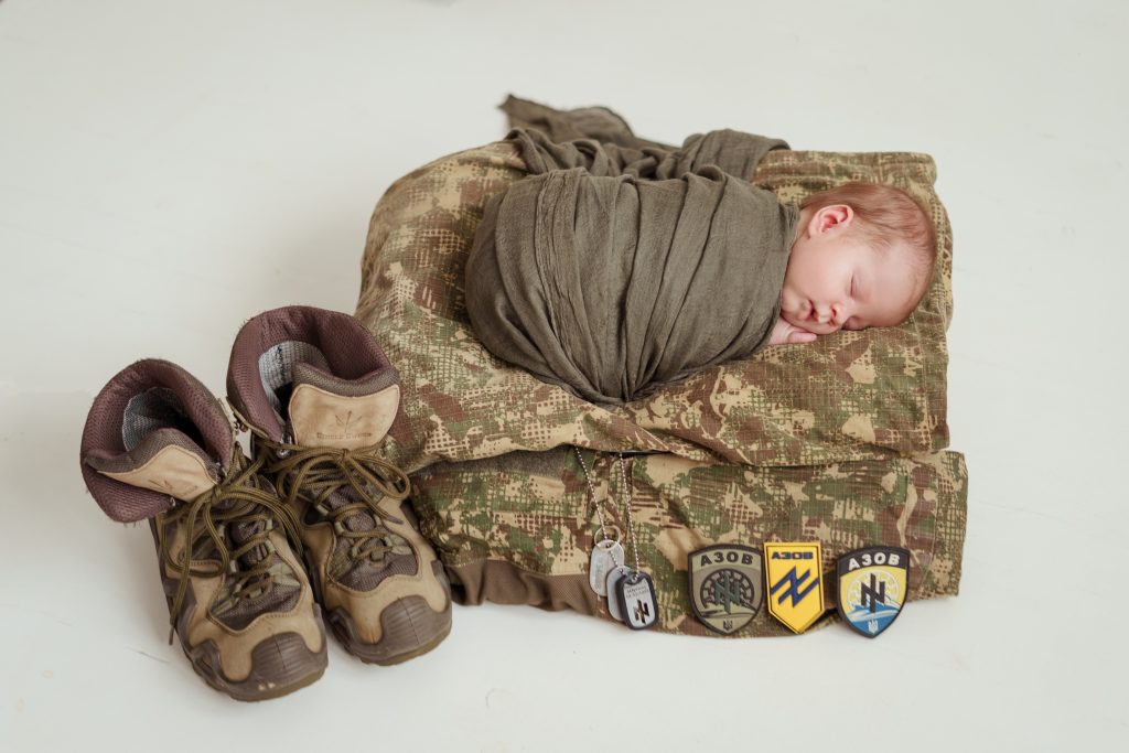Новонароджена дитина лежить на військовому одязі
