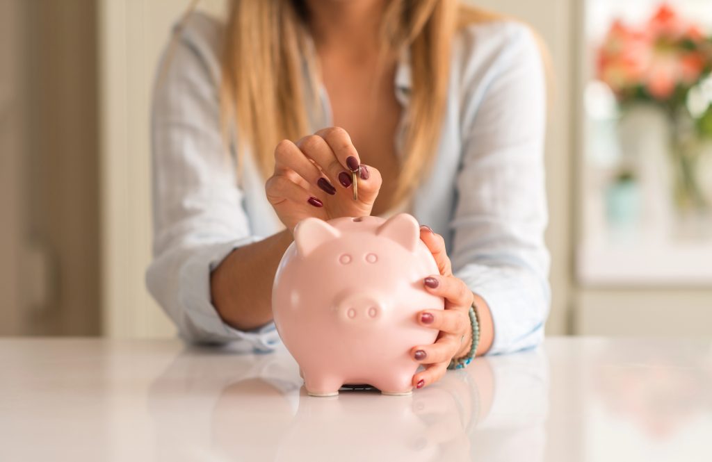 жінка кидає монету в скарбничку