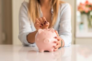 жінка кидає монету в скарбничку