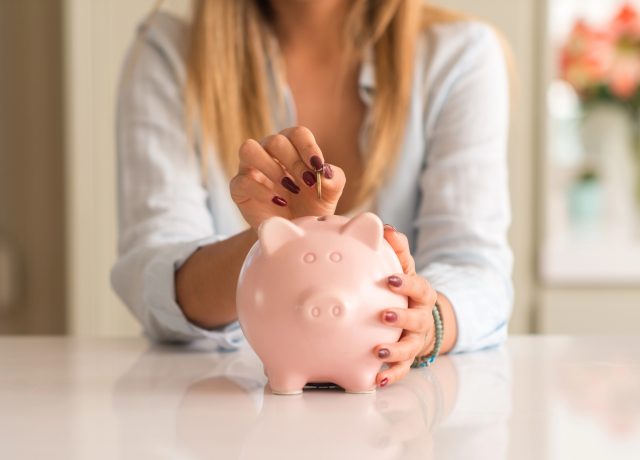 жінка кидає монету в скарбничку