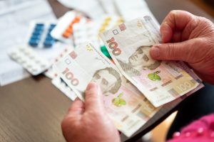 жінка тримає гроші, на фоні ліки