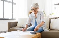 пенсіонерка в білій сорочці рахує і записує