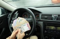 жінка тримає гроші в машині