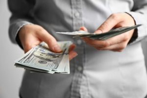 людина тримає долари