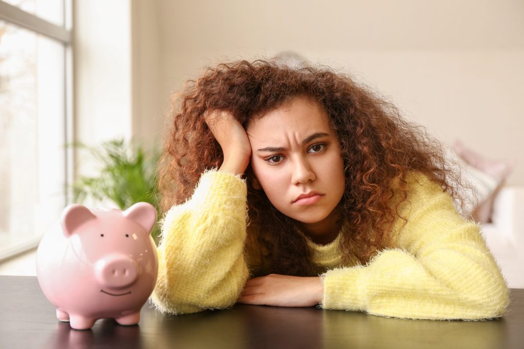 сумна кучерява дівчина в жовтому светрі біля скарбнички