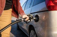 чоловік заправляє темне авто