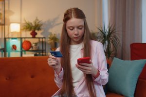 Дівчинка-підлітка, смартфон, банківська картка