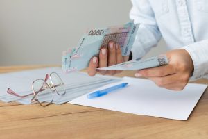 жінка тримає гроші, гривні, документи