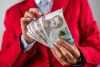 жінка в червоному костюмі тримає гривні, 1000 грн