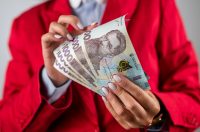 жінка в червоному костюмі тримає гривні, 1000 грн
