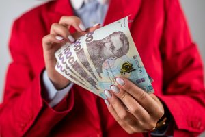 жінка в червоному костюмі тримає гривні, 1000 грн
